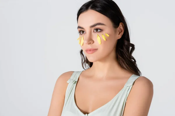 Giovane donna con petali gialli sul viso distogliendo lo sguardo isolato sul bianco — Foto stock