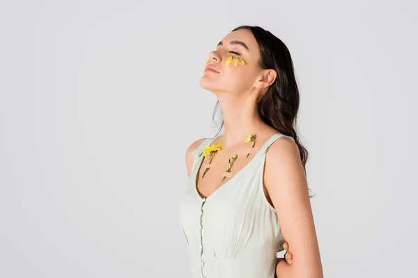 Brunette young woman with petals on face and plasters with yellow flowers on body isolated on white — Stock Photo