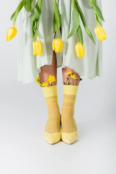 Partial view of woman in skirt with yellow tulips isolated on white — Stock Photo