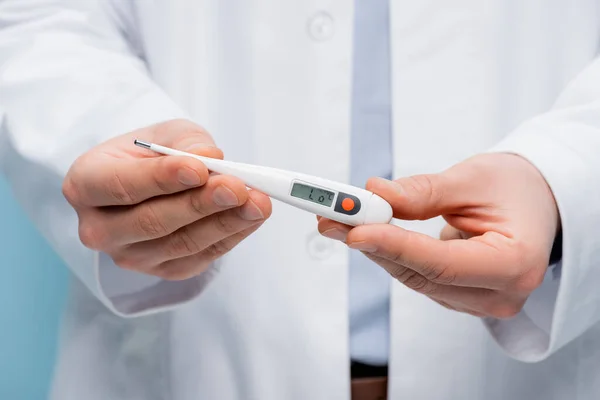 Partial view of doctor holding digital thermometer isolated on blue — Stock Photo