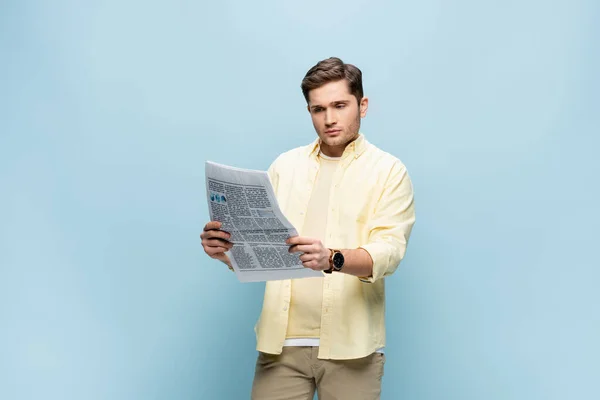 Jeune homme en chemise lecture journal sur bleu — Photo de stock