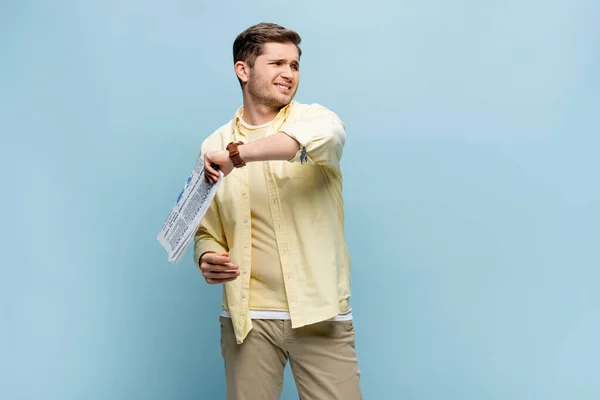 Upset young man in shirt holding newspaper on blue — Stock Photo