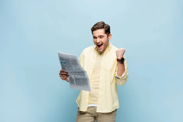 Joven emocionado en camisa leyendo el periódico en azul - foto de stock