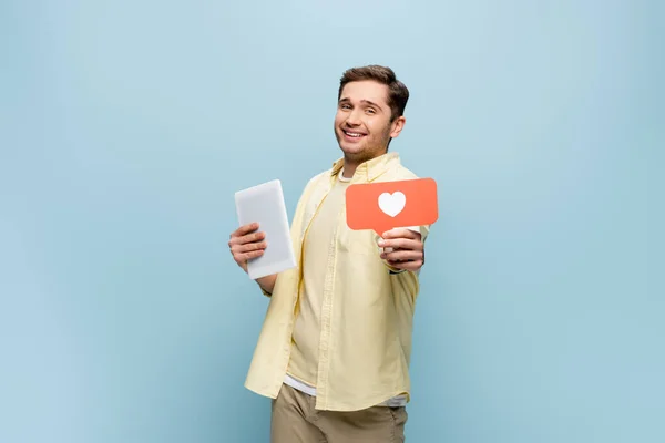 Cheerful man in shirt holding paper heart and digital tablet isolated on blue — Stock Photo