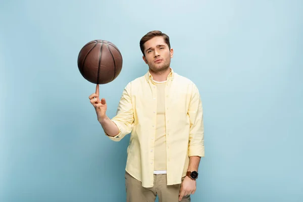 Jugador en camisa amarilla baloncesto giratorio en el dedo en azul - foto de stock