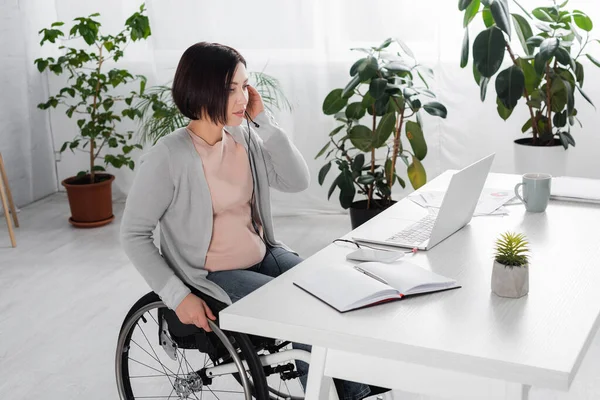 Behinderte Freiberufler nutzen Headset in der Nähe von Laptop und Notebook zu Hause — Stockfoto