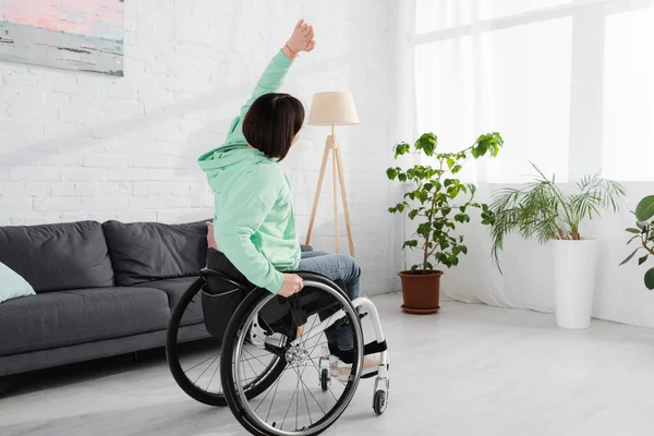 Woman working out while sitting in wheelchair in living room — Stock Photo