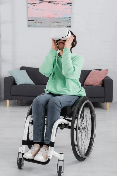 Erstaunte Frau mit Kopfhörer sitzt im Rollstuhl — Stockfoto