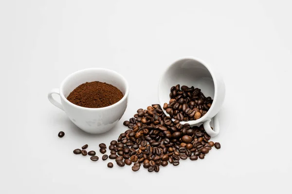 Gemahlener Kaffee und Bohnen in der Nähe von Tassen auf weiß — Stockfoto