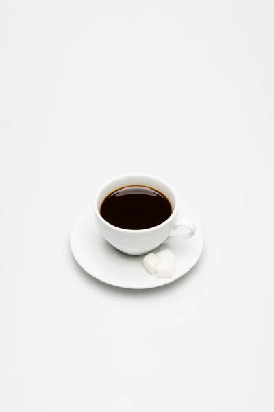 Cup of fresh coffee and sugar cubes on saucer on white — Stock Photo