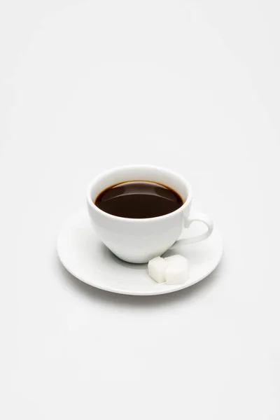 Tasse vorbereiteten Kaffee und Zuckerwürfel auf Untertasse auf weiß — Stockfoto