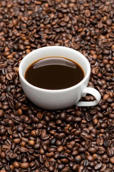 White cup with prepared coffee on brown beans — Stock Photo