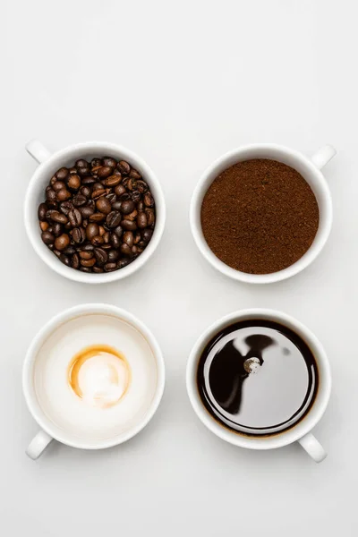 Top view of prepared americano near fresh ground coffee and beans in cups on white — Stock Photo