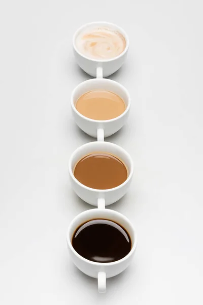 Different prepared coffee drinks with milk on white — Stock Photo