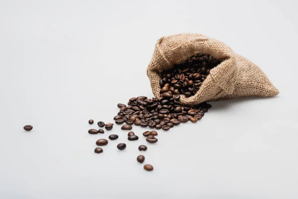 Hessian sack bag with roasted coffee beans on white — Stock Photo