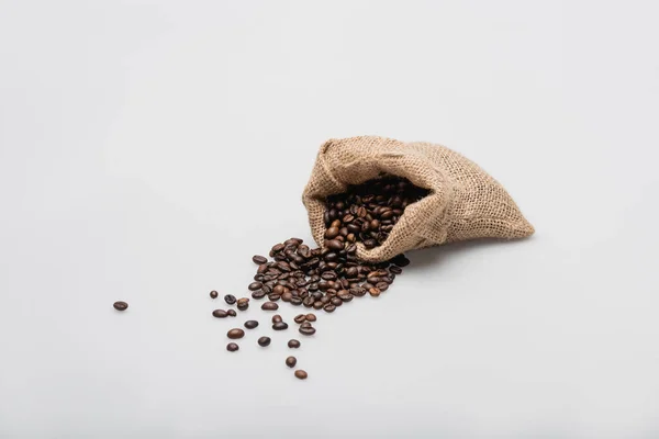 Sac sac hessian avec grains de café torréfiés sur blanc — Photo de stock