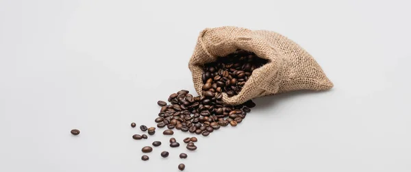 Sac sac hessian avec grains de café torréfiés sur blanc, bannière — Photo de stock