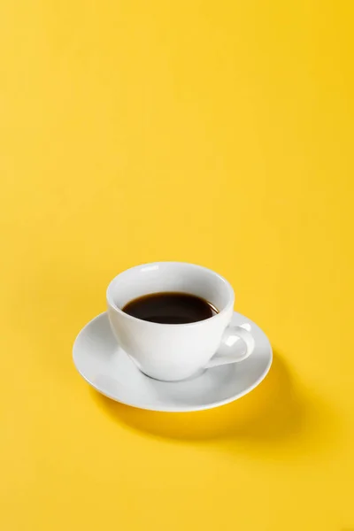 Black coffee in white mug on yellow background — Stock Photo