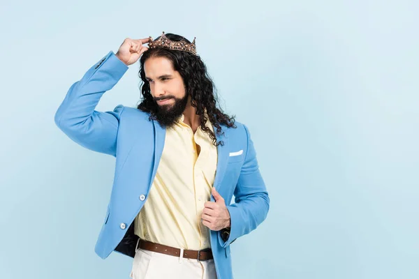 Hombre hispano barbudo sonriendo y llevando corona aislada en azul — Stock Photo