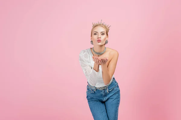 Mulher loira em coroa de luxo enviando beijo de ar isolado em rosa — Fotografia de Stock