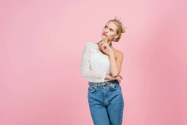 Mujer rubia pensativa en la corona de lujo de pie aislado en rosa — Stock Photo