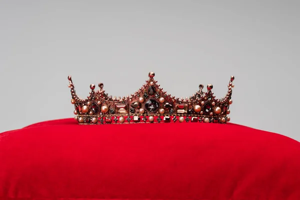 Coroa de luxo na almofada de veludo vermelho isolado em cinza — Fotografia de Stock