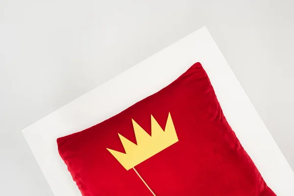 Вид зверху на паперову корону на паличці і червону подушку ізольовано на сірому — стокове фото