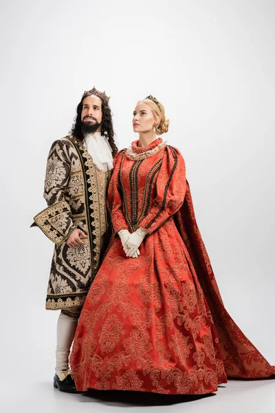Full length of historical interracial husband and wife in crowns and medieval clothing on white — Stock Photo