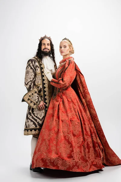 Longueur totale de couple interracial historique en couronnes et vêtements médiévaux debout sur blanc — Photo de stock