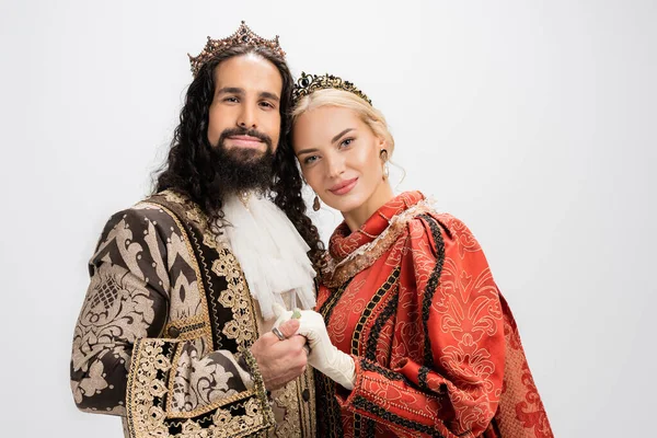 Happy historical interracial couple in crowns and medieval clothing isolated on white — Stock Photo