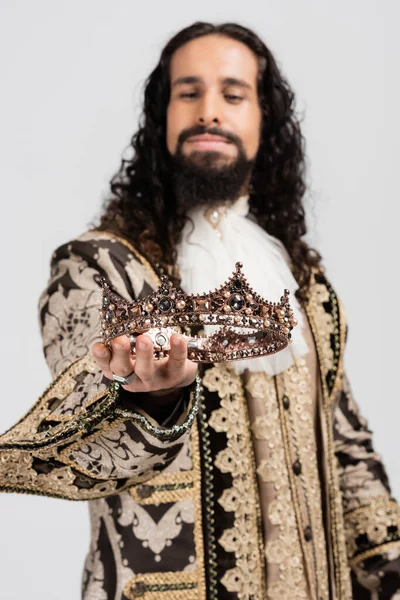 Blurred hispanic king in medieval clothing holding crown isolated on white — Stock Photo