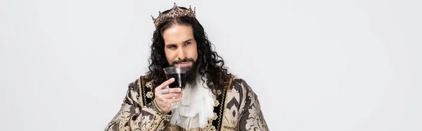 Hispanic king in medieval clothing and crown holding glass of red wine isolated on white, banner — Stock Photo