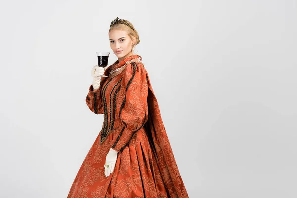 Queen in dress and golden crown holding glass and drinking red wine on white — Stock Photo