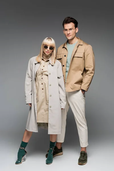 Full length of trendy young couple posing on grey — Stock Photo