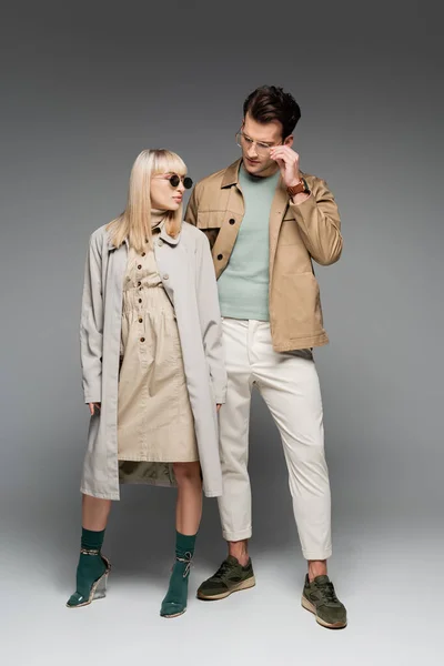 Full length of stylish young couple posing on grey — Stock Photo