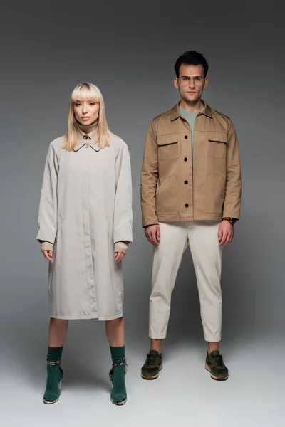 Tutta la lunghezza dei modelli alla moda in posa mentre in piedi sul grigio — Foto stock