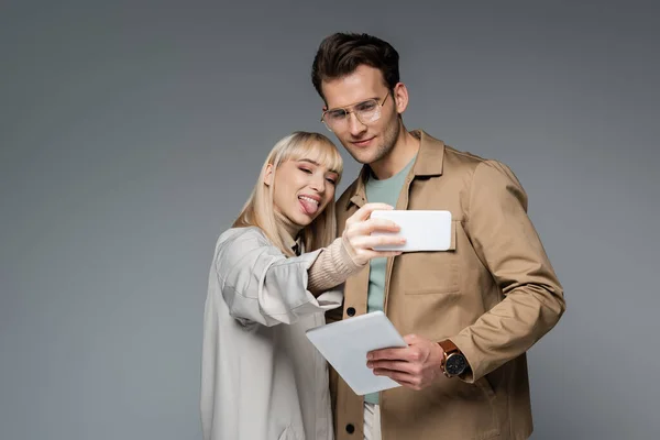 Jeunes modèles posant tout en prenant selfie isolé sur gris — Photo de stock