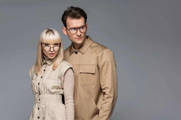 Jeunes modèles élégants dans des lunettes posant isolé sur gris — Photo de stock