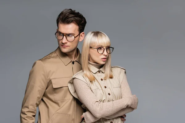 Jeunes modèles à la mode dans des lunettes posant isolé sur gris — Photo de stock