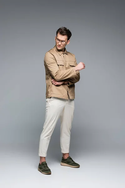 In voller Länge trendiger Mann im stylischen Outfit posiert auf grau — Stockfoto