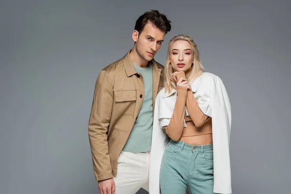 Stylish models in pants and jackets posing isolated on grey — Stock Photo