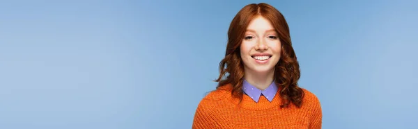 Happy redhead woman in orange sweater isolated on blue, banner — Stock Photo