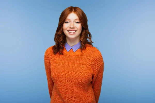Glücklich rothaarige Frau in orangefarbenem Pullover isoliert auf blau — Stockfoto
