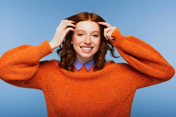 Femme rousse souriante en pull orange isolé sur bleu — Photo de stock
