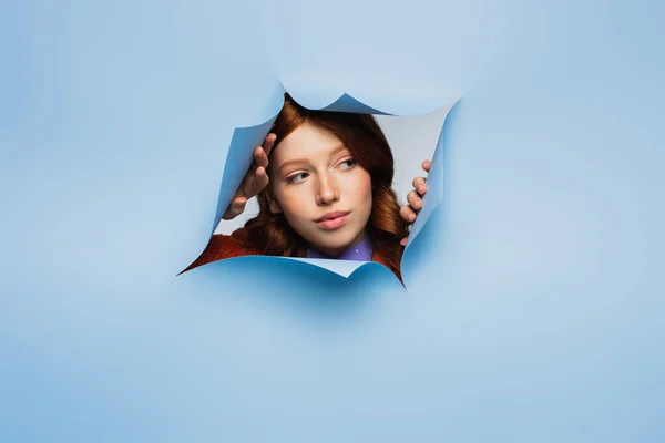 Ruiva jovem mulher olhando para longe em azul rasgado fundo — Fotografia de Stock
