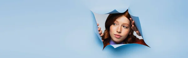 Ruiva jovem mulher olhando para longe em azul rasgado fundo, banner — Fotografia de Stock