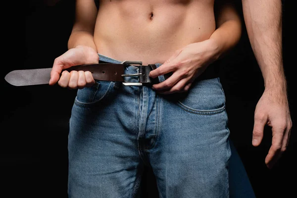 Cropped view of woman touching belt of man isolated on black — Stock Photo