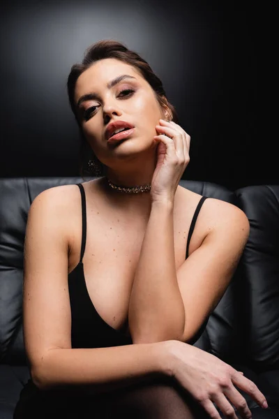 Seductive woman in necklace, earrings and slip dress on black — Stock Photo