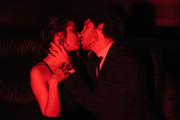 Iluminação vermelha no casal sexy beijando no preto — Fotografia de Stock
