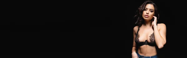 Giovane donna bruna con seno grande in reggiseno di pizzo guardando la fotocamera isolata sul nero, banner — Foto stock